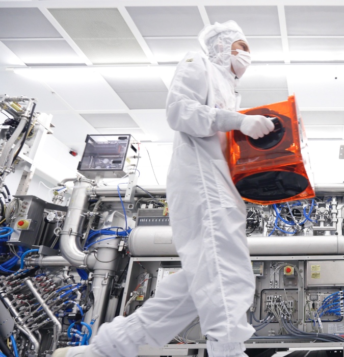 ASML man in bedrijfskleding verplaatste een doos in 'the clean box room'. The enable affordable microelectronics that improve the quality of life. They invent, develop, manufacture in service advanced technology for high-tech lithography, metrology and software solutions for the semiconductor industry.